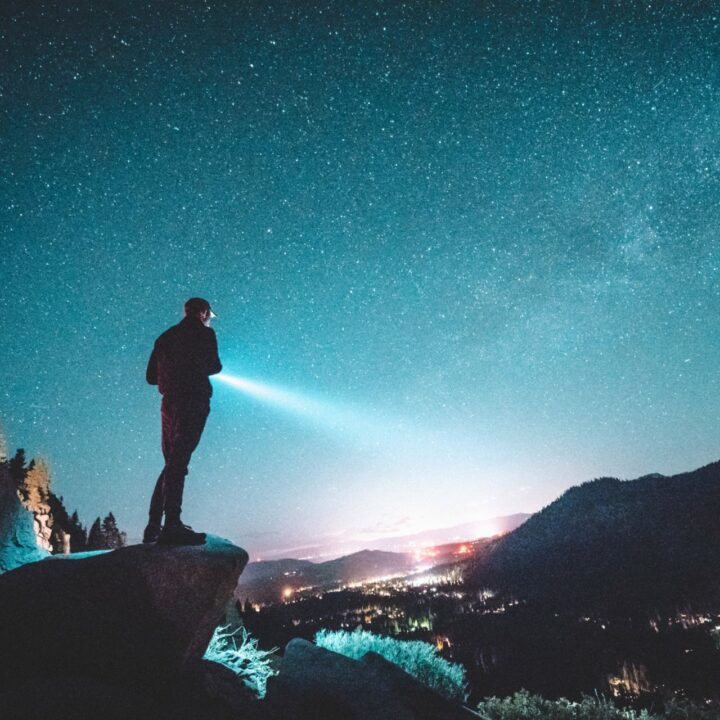 man overlooking a cliff with a flash light