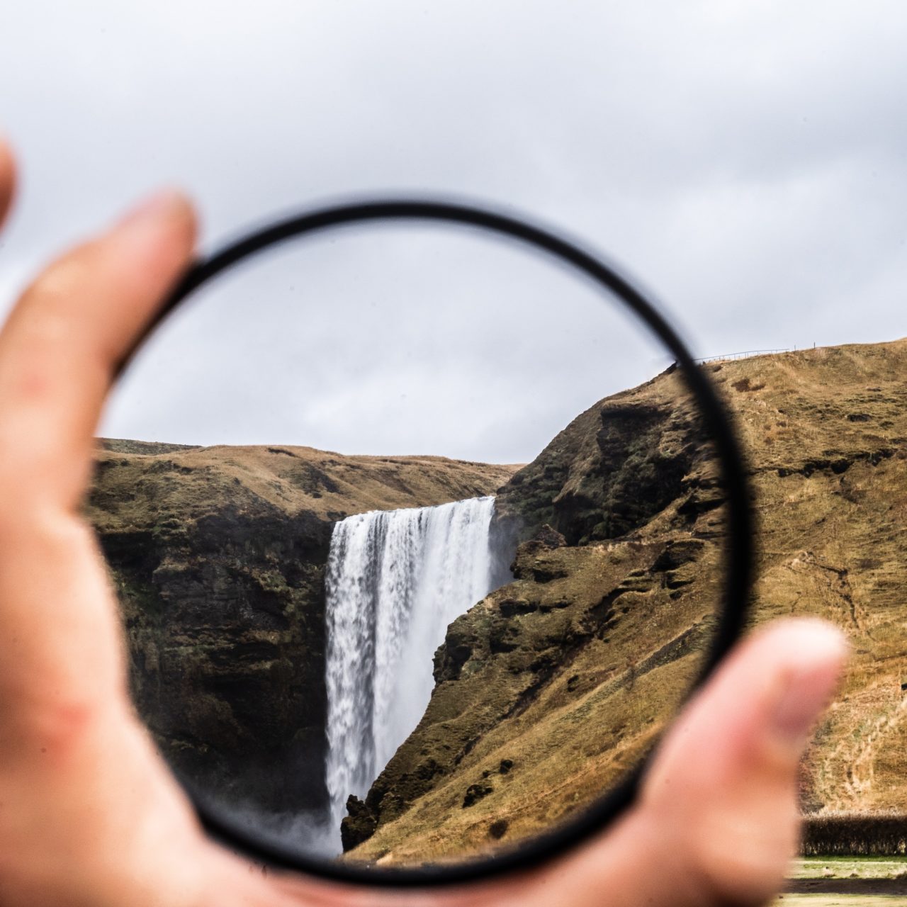 person looking at a waterfall through a lens