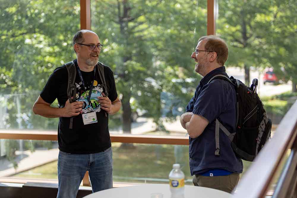 two men talking against a window