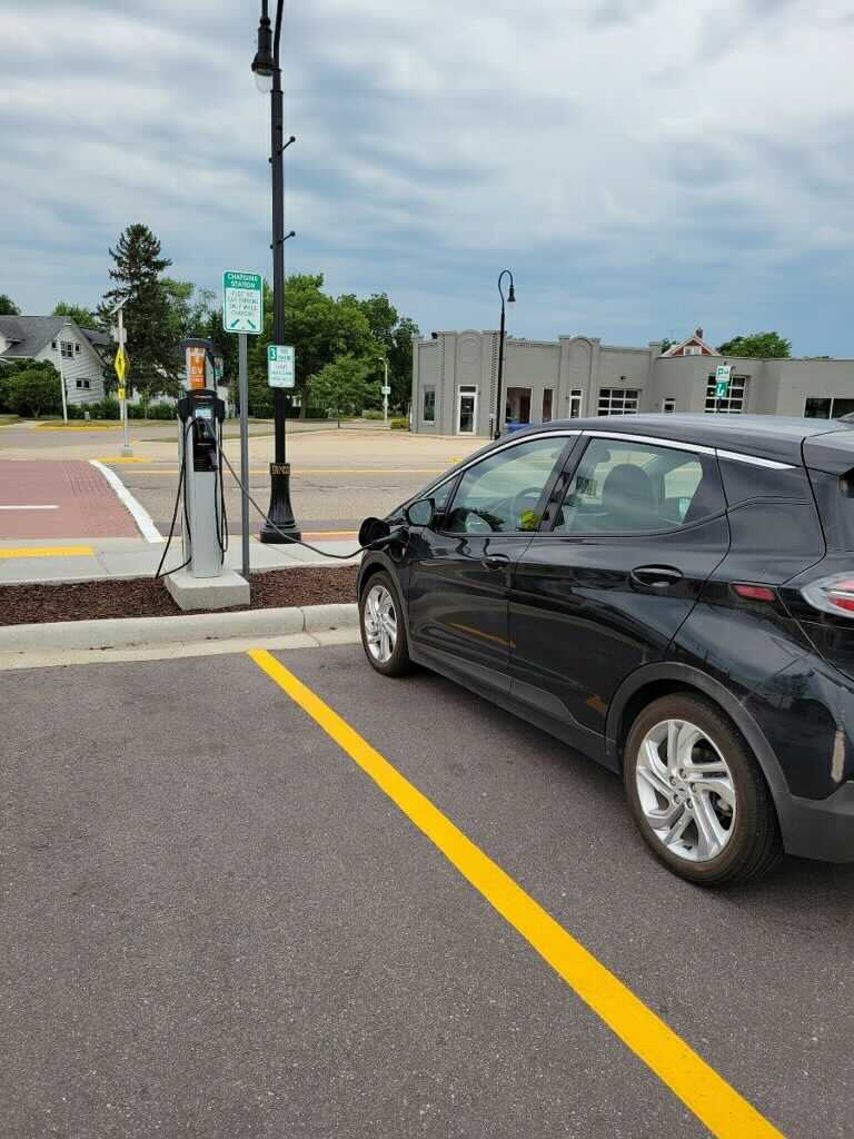 A black Chevy Bolt charges in a parking lot.