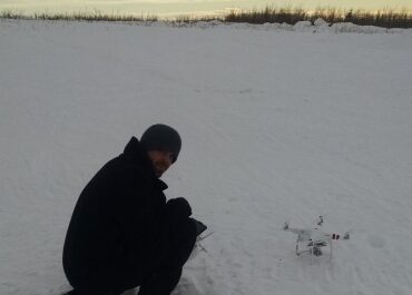 man kneeling down to a drone on the ground